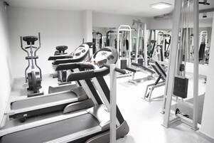 Un gimnasio con cintas de correr, elípticas y equipos de levantamiento de pesas.