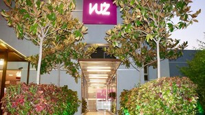 A building entrance with a 'WZ' sign, surrounded by trees and shrubs. - VU'Z Hotel Apt (Blat)