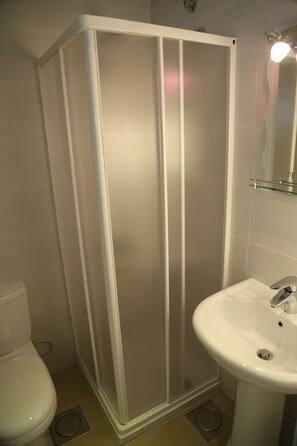 A bathroom with a shower enclosure, a toilet, and a sink. - VU'Z Hotel Apt (Blat)