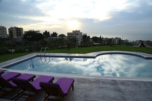A swimming pool with lounge chairs and a view of surrounding buildings. - VU'Z Hotel Apt (Blat)