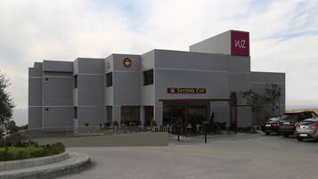 Un edificio moderno con un letrero de 'Second Cup', un logo de 'Wuz' y un área de estacionamiento con automóviles.