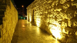 A narrow alleyway with stone walls and a paved path, illuminated by street lamps. - VU'Z Hotel Apt (Blat)