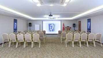 A conference room with rows of chairs, a podium, and a presentation screen.