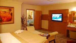 Una habitación de hotel con una cama, televisor, escritorio y un cuadro en la pared.