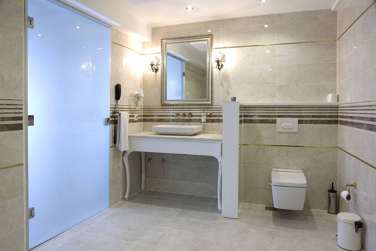 A modern bathroom with a white sink, a large mirror, and a toilet.