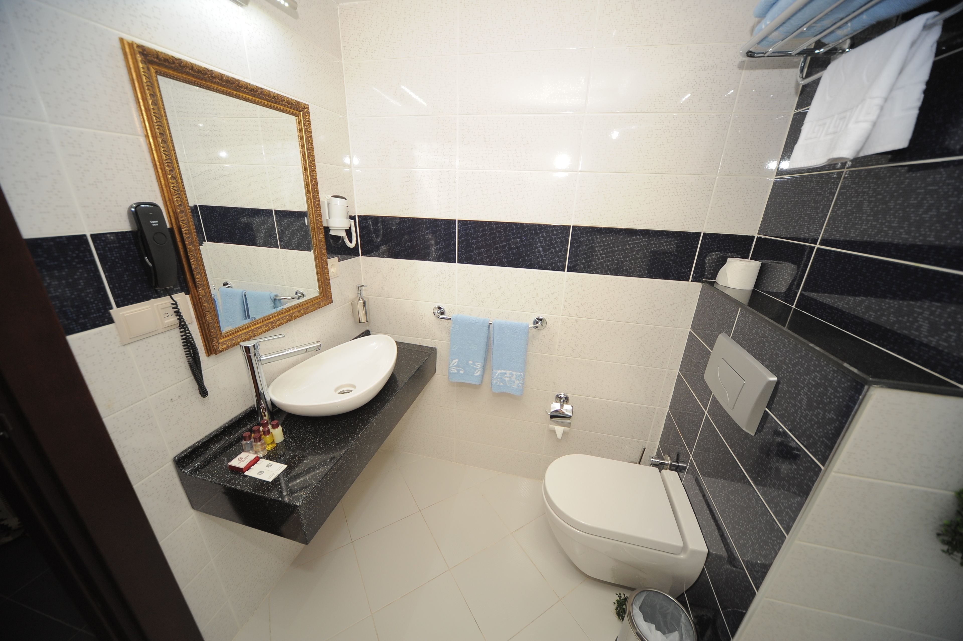 A bathroom with a white sink, a mirror, a toilet, and a towel rack.