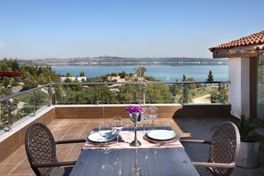 A balcony with a table set for two, overlooking a coastal landscape. - Golden Lake Hotel (Adana)