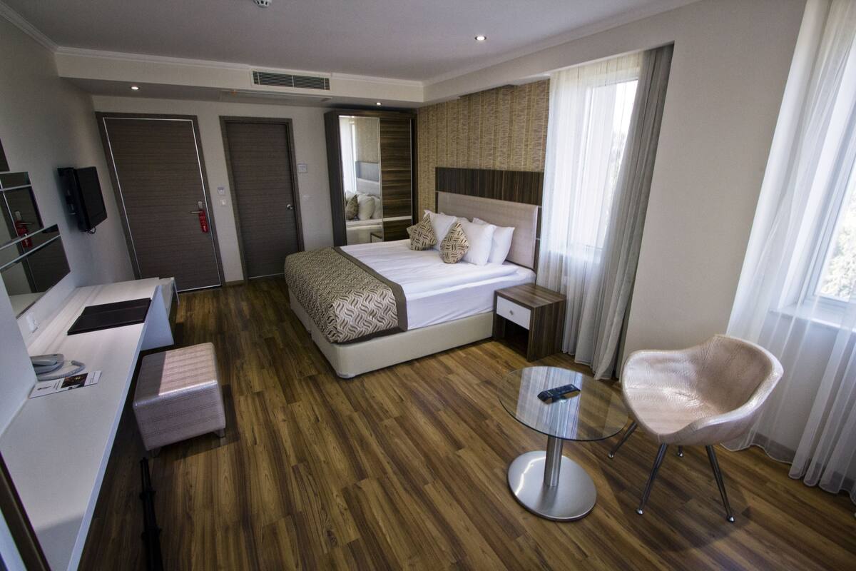 A hotel room with a bed, bedside table, chair, and a small round table.