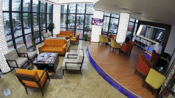 A spacious lobby with large windows, comfortable seating, and a bar area. - Yol Is Holiday Adana (Adana)