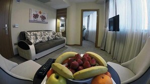 A living room with a sofa, a coffee table with fruit, a TV, and a remote control. - Yol Is Holiday Adana (Adana)