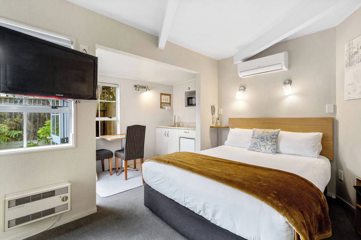 Een hotelkamer met een bed, een televisie, een bureau en een stoel.