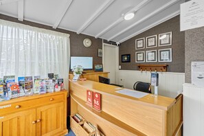 Un mostrador de recepción con encimera de madera, una computadora y certificados enmarcados en la pared.