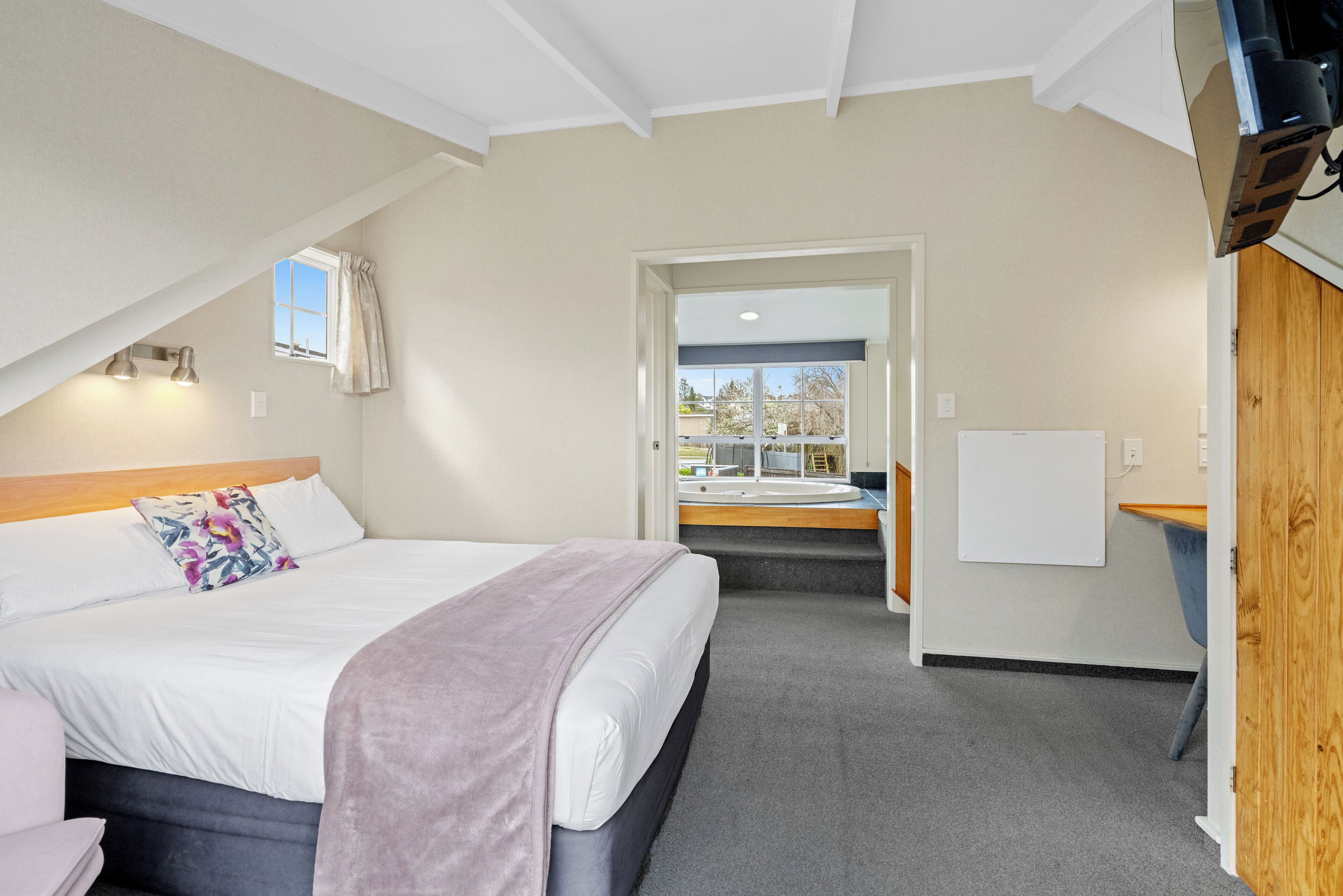 Quarto com cama, escrivaninha e vista para o exterior.