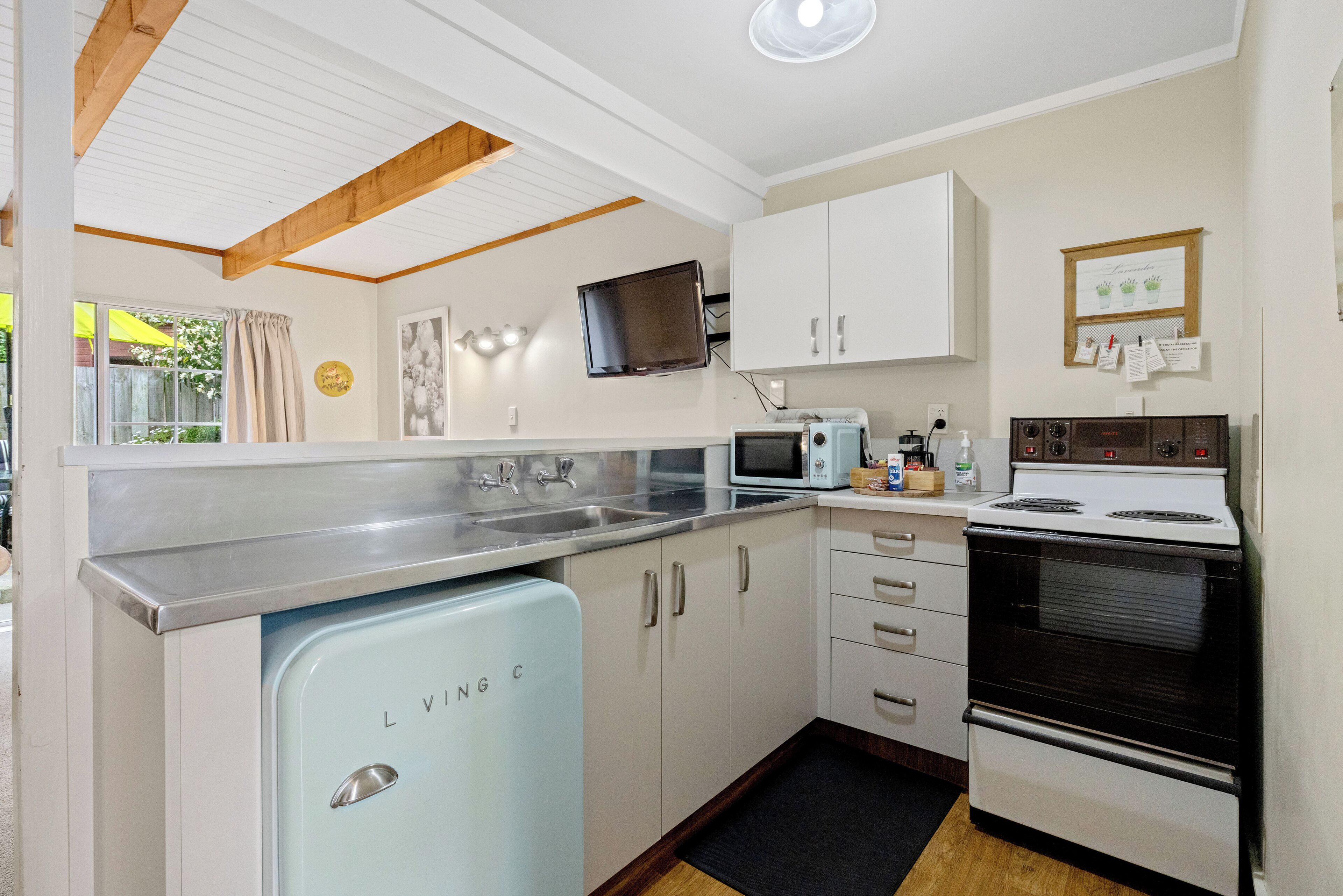 A compact kitchen with a vintage refrigerator, a microwave, a stove, and white cabinets.