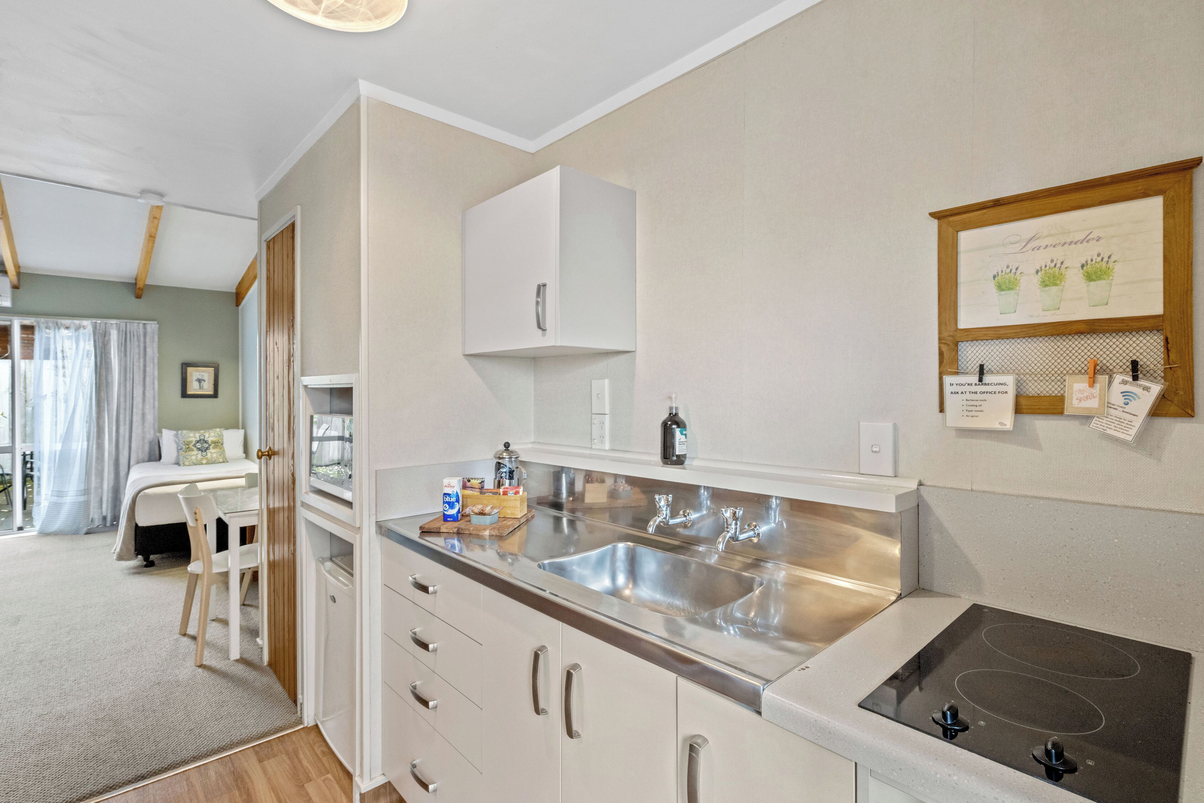 A modern kitchen with a stainless steel sink, white cabinets, and a wooden countertop.
