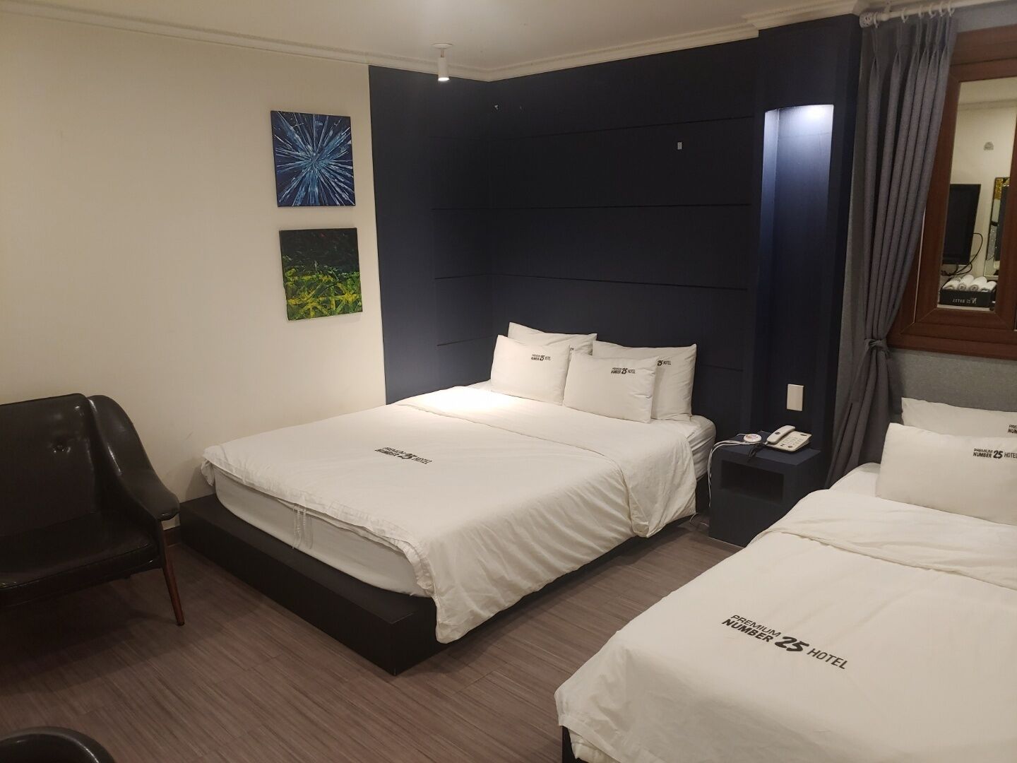 A hotel room with two beds, a desk, and a chair.
