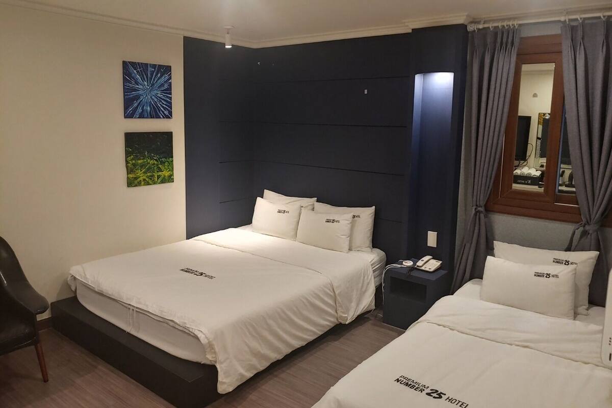 A hotel room with two beds, a nightstand, a chair, and artwork on the walls.
