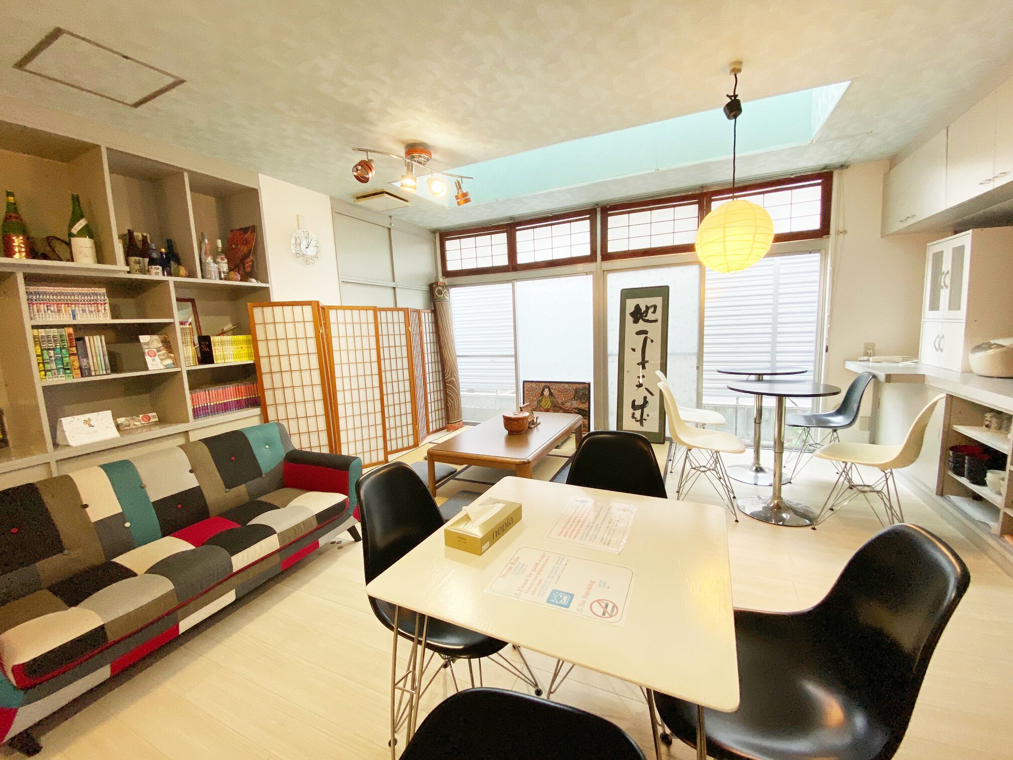 Un intérieur moderne comprenant un canapé, une table à manger, des chaises et des étagères où sont disposés divers objets.