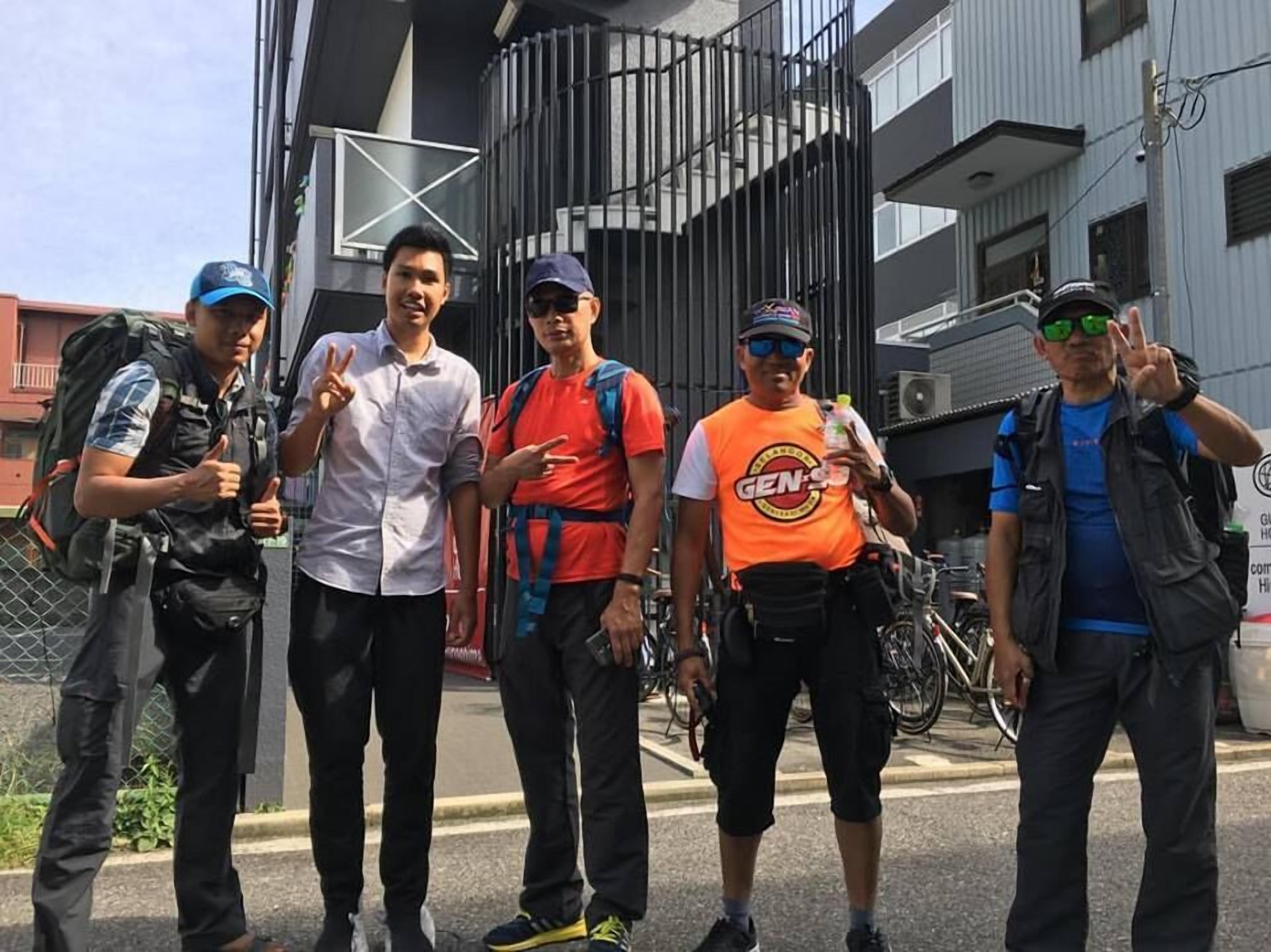 A group of people standing on a street with bicycles and a building in the background.