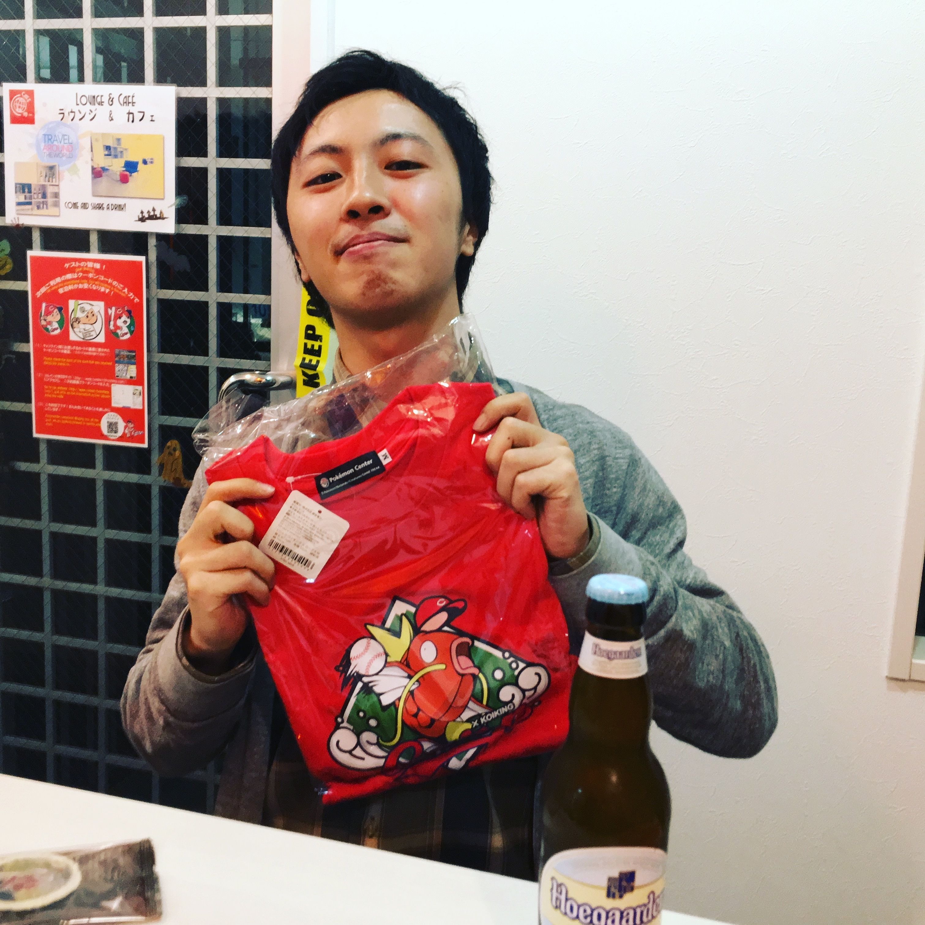 A person holding a red bag with a cartoon character, standing next to a bottle of beer and a glass.