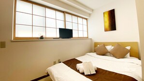 A hotel room with a large window, a bed with white and brown bedding, and a flat-screen TV on a shelf above the bed. - OUCHI HOTEL Yokogawa (Hiroshima)