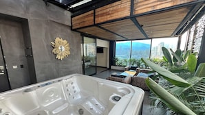 A modern indoor space with a large hot tub, a sunburst mirror, and a view of a cityscape through large windows. - Hotel 47 Medellin Street (Medellín)