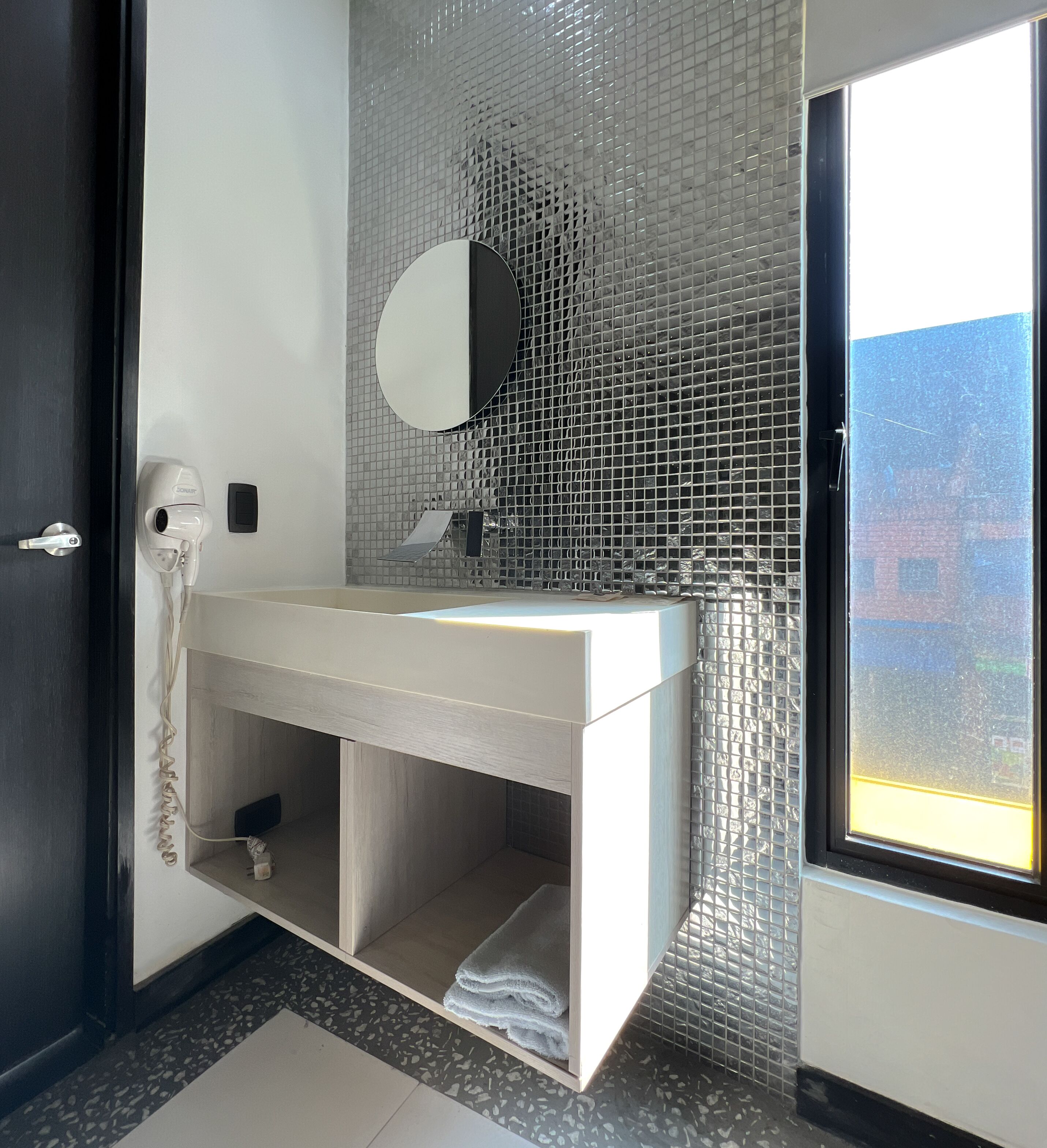 A modern bathroom with a white vanity, a mirror, and a glass mosaic backsplash.