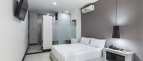 Un dormitorio moderno con cama, televisor montado en la pared, mesita de noche con lámpara y equipo de aire acondicionado.