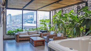 A balcony with wicker furniture, a hot tub, and a view of a cityscape. - Hotel 47 Medellin Street (Medellín)