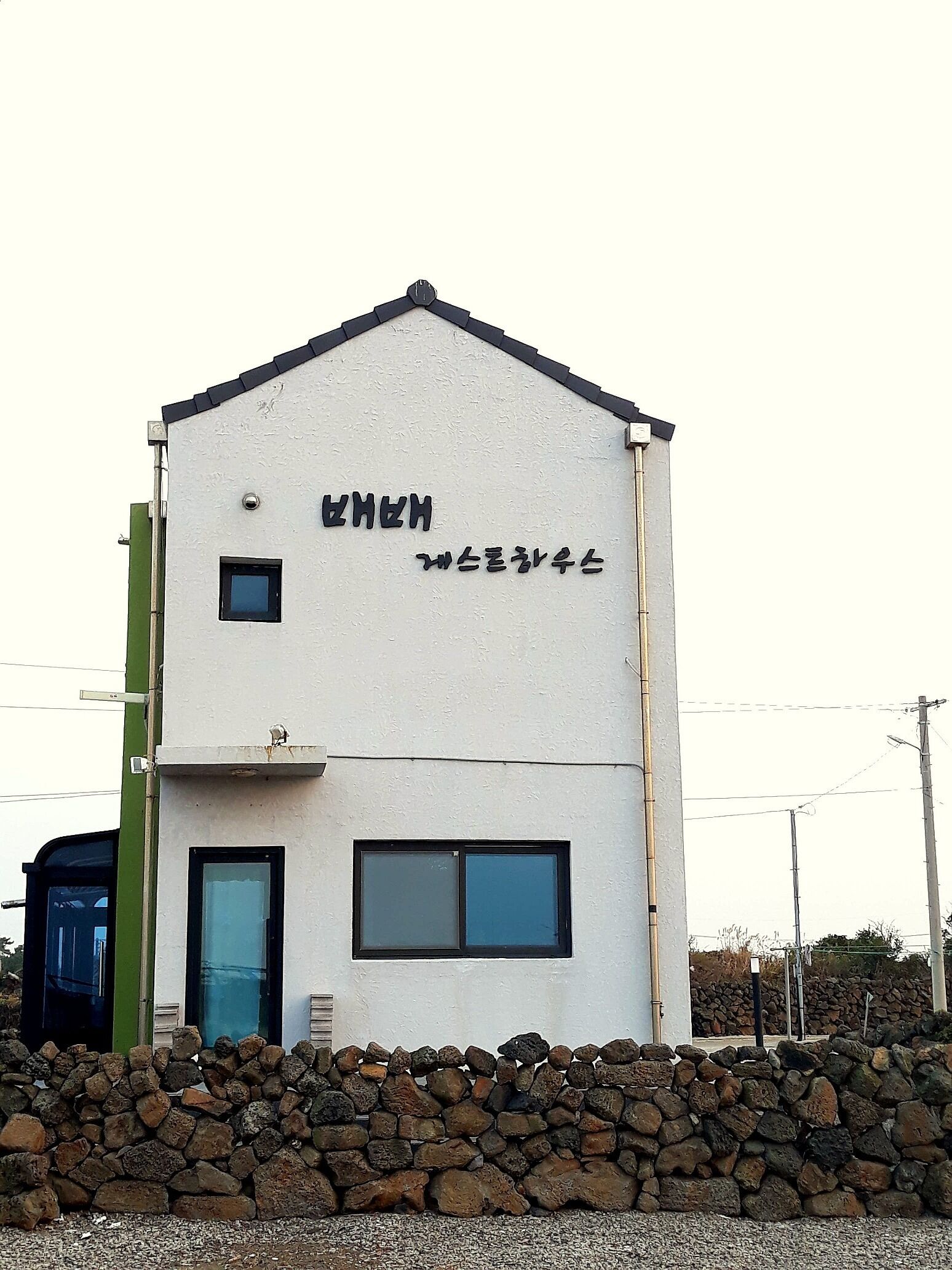 A two-story building with a white exterior and black trim. It has a small entrance with a door and windows on the second floor.