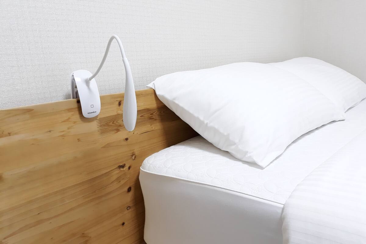 A wooden headboard with a white pillow and a white mattress.