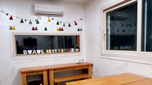 Una habitación con una mesa de madera y bancos, una ventana con vistas y un aire acondicionado instalado en la pared.