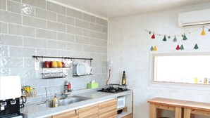 Una cocina moderna con salpicadero de azulejos grises, armarios de madera, una estufa integrada y un comedor con mesa y sillas de madera.