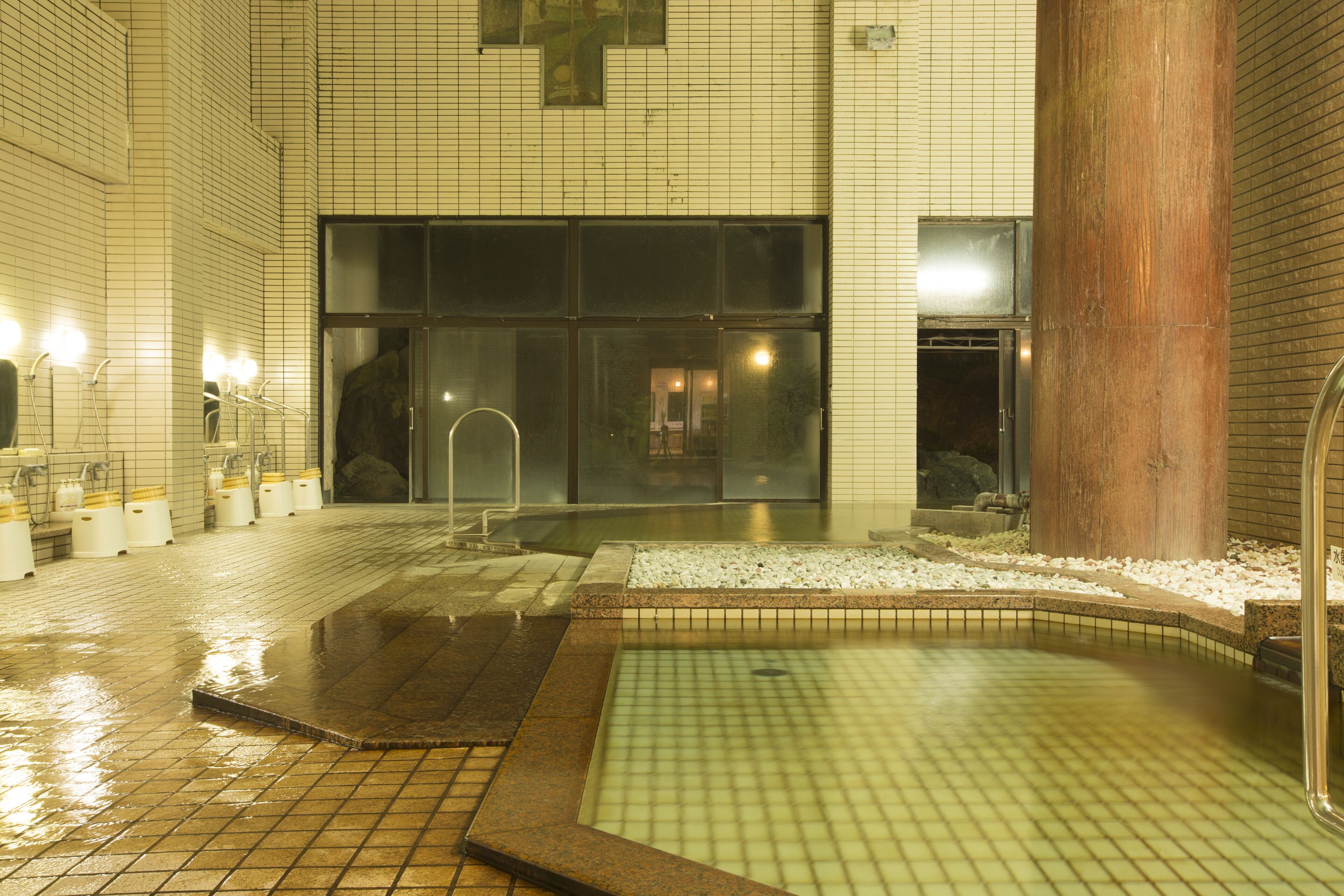 Un área de spa con suelo de baldosas, piscina y un gran pilar de madera.