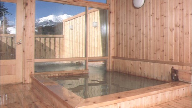 A wooden sauna with a glass window offering a view of snow-capped mountains. - Hotel Gute Welle (Matsumoto)