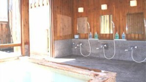 A wooden bathroom with a large bathtub, a sink with a mirror, and a shower area. - Hotel Gute Welle (Matsumoto)