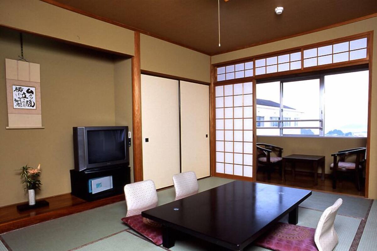A traditional Japanese-style room with tatami flooring, a low table, and a television.