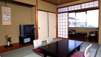 Una habitación tradicional japonesa con suelo de tatami, una mesa baja y un televisor.