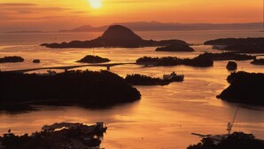 Paisaje costero con un puente, barcos e islas al atardecer.