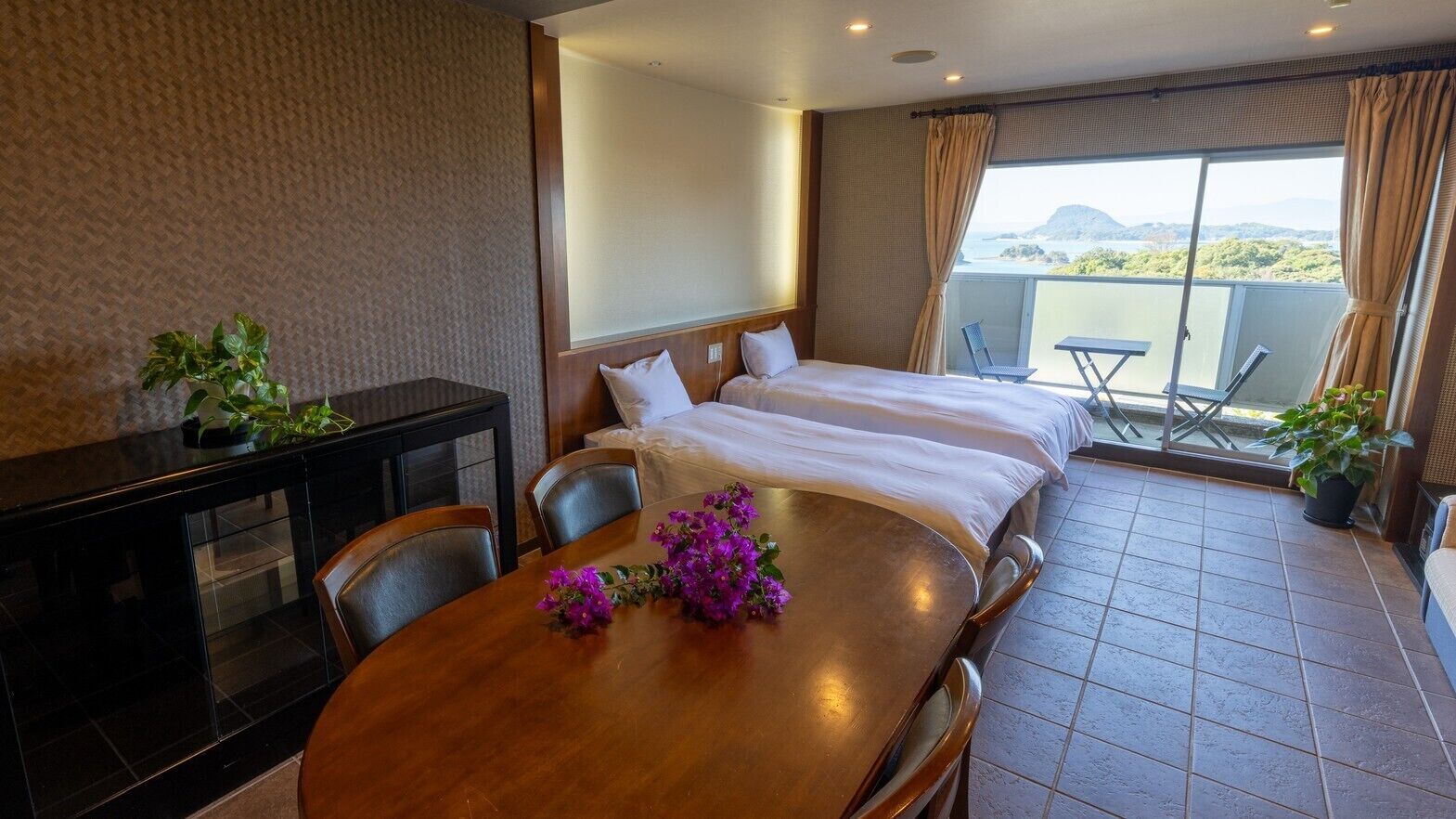 Ein Hotelzimmer mit Balkon, einem Esstisch mit Stühlen und einem Bett mit weißer Bettwäsche.