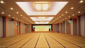 A hotel room with tatami mat flooring, a large window, and a chandelier.