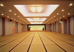 A hotel room with tatami mat flooring, a large window, and a chandelier.