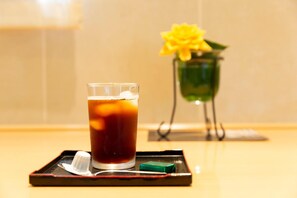 A glass of iced tea on a tray with a napkin and a green soap bar. - Idaimae Green Hotel (Saga)