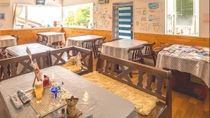 Un restaurante acogedor con paredes y mesas de madera, que presenta un mantel a cuadros, una botella y un control remoto en una de las mesas.