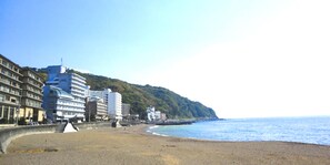 A beach with buildings and a hill in the background.