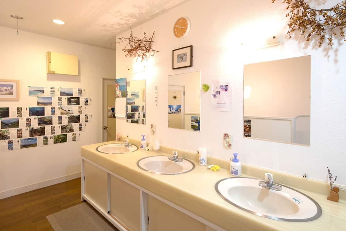 Ein Badezimmer in einem Hotel mit zwei Waschbecken, einem Spiegel, einer Uhr und einer Wand mit Fotos.