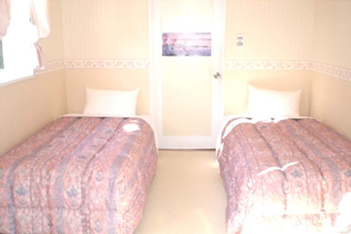 Ein Hotelzimmer mit zwei Betten, einer Tür und einem Fenster.