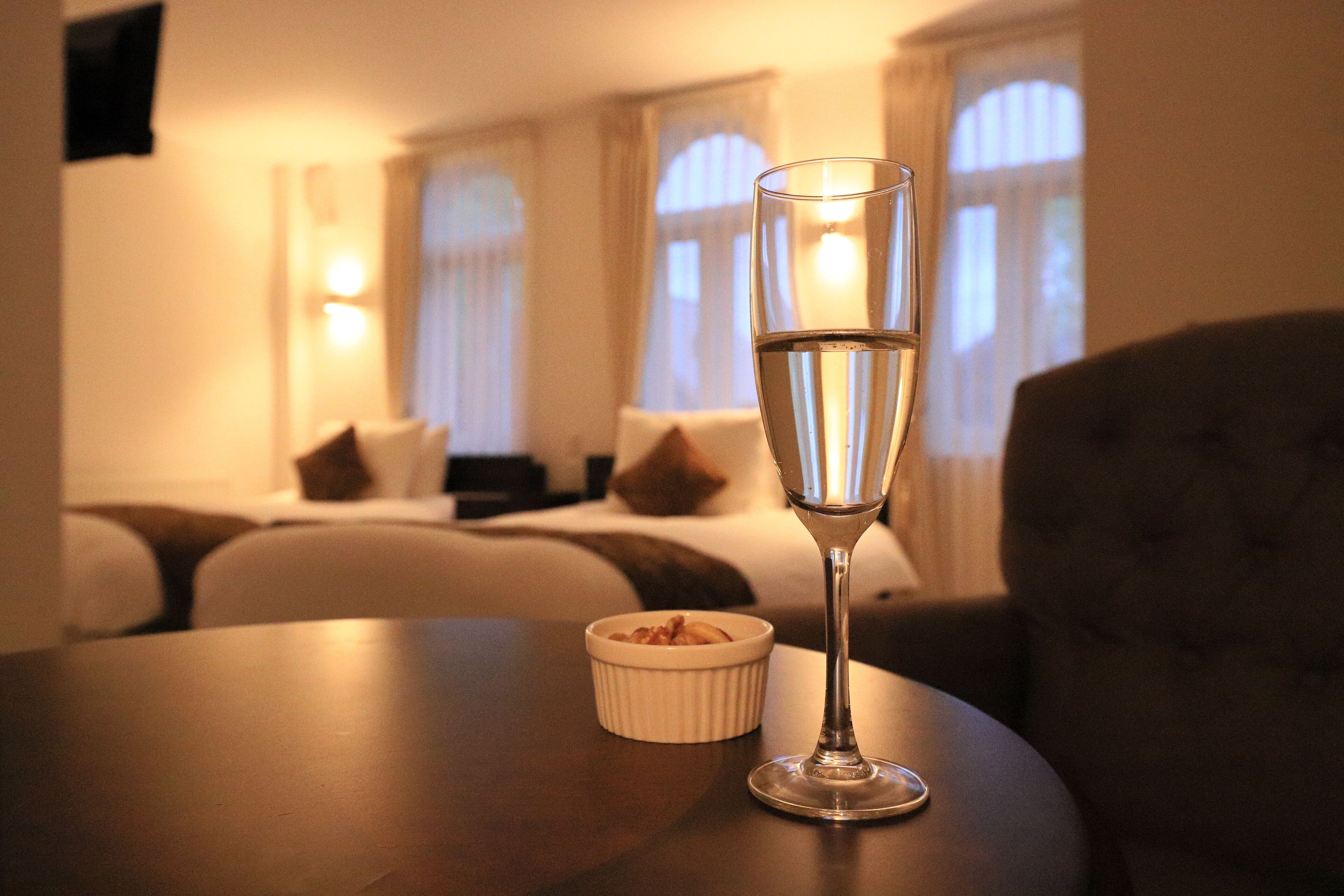 Een kamer met een bed, een nachtkastje met een glas water en een kleine schaal eten.
