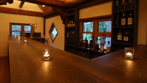 A bar area with wooden tables, candles, and shelves of liquor bottles. - BLISS Villa TSUBAKI (Kutchan)
