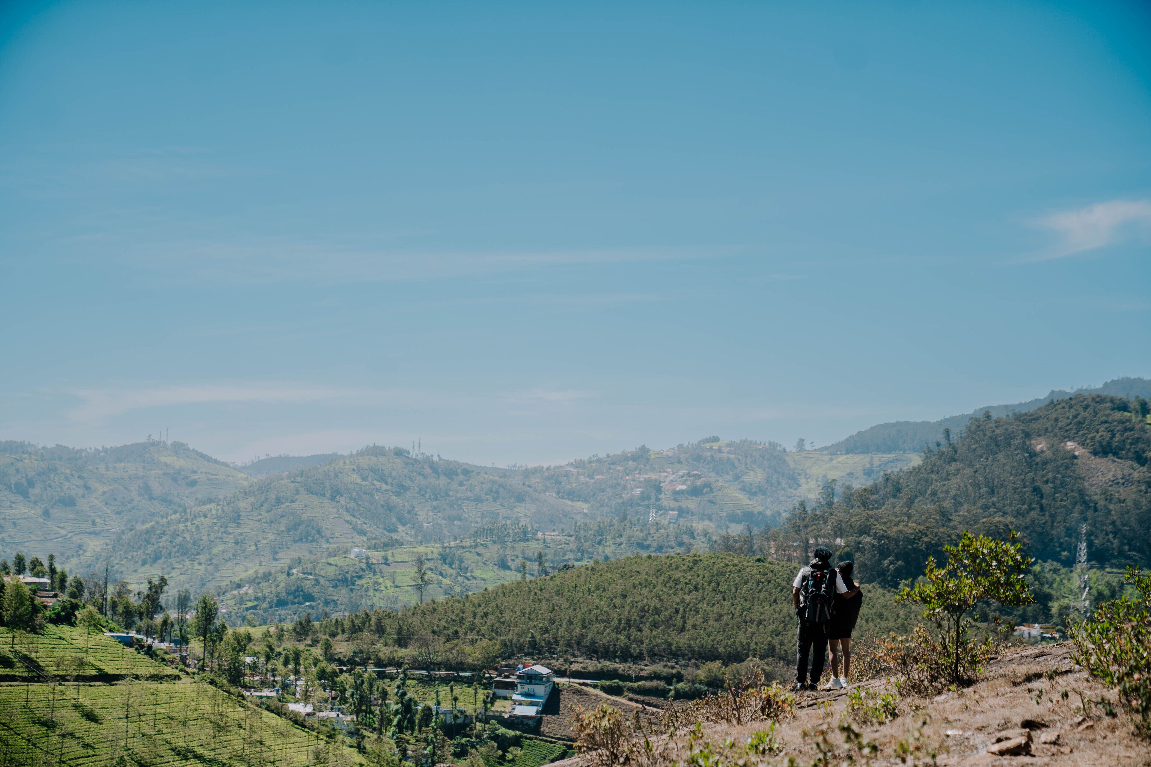 A hilly landscape with a person standing on a hill overlooking a valley.